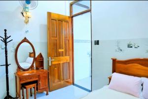 a bedroom with a bed and a mirror and a door at Nybipu Homestay in Phan Rang
