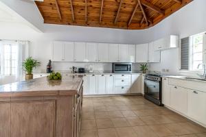 cocina con armarios blancos y techo de madera en Villa Amore Jamaica - Between Montego Bay & Ochi Rios Includes Cook, en Discovery Bay