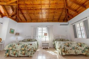two beds in a bedroom with a wooden ceiling at Villa Amore Jamaica - Between Montego Bay & Ochi Rios Includes Cook in Discovery Bay