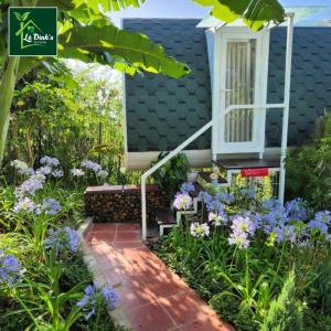 un giardino con fiori viola e una casa di Lê Đinh’s House a Di Linh