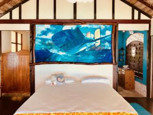 1 dormitorio con 1 cama con una pintura en la pared en Rangiroa Bliss en Tiputa
