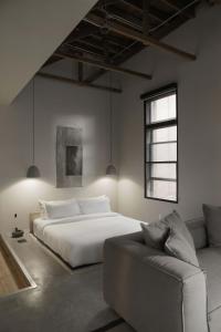 1 dormitorio con cama blanca y sofá en kodō hotel, en Los Ángeles