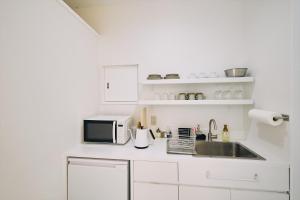 高知的住宿－「まちのアトリエ」STAY UWU 004，白色的厨房配有水槽和微波炉