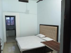 a bedroom with a bed and a table and a window at MAHENDRA HOME STAY in Faizābād