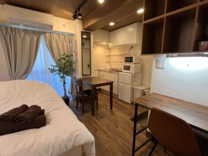 東京にあるCozy inn Oyamaのベッド、テーブル、キッチンが備わる客室です。