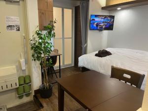 東京にあるCozy inn Oyamaのベッド、テーブル、テレビが備わる客室です。