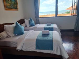 two beds in a hotel room with a window at Sea View Villa @ Nongsa Resort in Telukmataikan