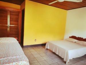 a bedroom with two beds and a yellow wall at La Purruja Lodge in Golfito