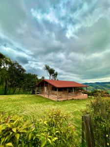 uma cabana de madeira com um telhado vermelho num campo em Refugio Aventura, hermosa cabaña y acogedores glampings en Tabio, cerca a Bogotá em Tabio