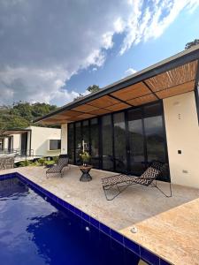 a house with a swimming pool and two chairs at Wayma House in Villeta