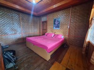 a bedroom with a bed with pink sheets and pillows at Nias Shady Palm surfcamp in Lagudri