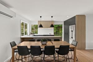 a kitchen and dining room with a wooden table and chairs at Mollymook Golden Sands in Narrawallee