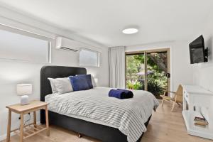 a bedroom with a bed with blue pillows on it at Mollymook Golden Sands in Narrawallee