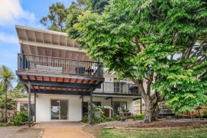 an apartment building with a balcony and a tree at Mollymook Golden Sands in Narrawallee