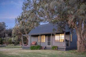 uma casa cinzenta com uma árvore em frente em Red Rocks Golf & Accommodation - Phillip Island em Cowes