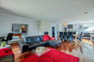 a living room with a black leather couch and a red rug at Rivervale Retreat - Spacious Family Living in Perth
