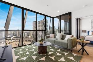 een woonkamer met een bank en grote ramen bij Stylish & Central w Stunning City Views & Balcony in Melbourne