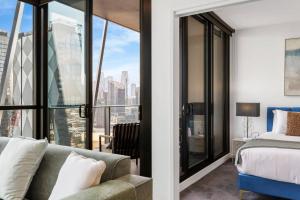 een slaapkamer met een bank, een bed en glazen ramen bij Stylish & Central w Stunning City Views & Balcony in Melbourne