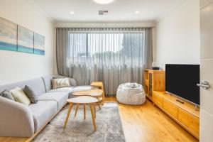een woonkamer met een bank en een tv bij Como Sora - A Breezy Tranquil Oasis on the Coast in Perth