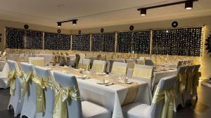 un salón de banquetes con mesas blancas y sillas con arcos de oro en Club Hotel en Glen Innes