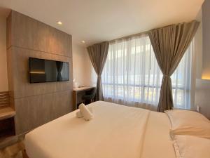 a bedroom with a bed with a tv and a window at Mc Hotel Fairview in Manila