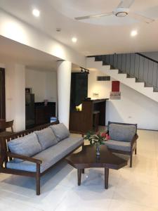 ein Wohnzimmer mit einem Sofa, einem Tisch und einer Treppe in der Unterkunft Ivory Villas Hòa Bình in Hòa Bình