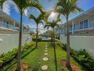 a pathway with palm trees in front of a building at Arraial d Ajuda - Casa Oásis - Residencial Monte das Oliveiras in Porto Seguro