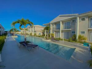 a swimming pool with two chairs in front of a building at Arraial d Ajuda - Casa Oásis - Residencial Monte das Oliveiras in Porto Seguro