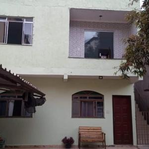 un banco sentado fuera de una casa con una ventana en Hostel Santa Luzia en Viçosa