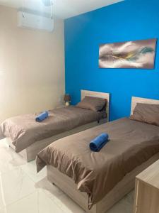 - 2 lits dans une chambre aux murs bleus dans l'établissement Modern SeaFront 3bedrooms Apartment, à San Pawl il-Baħar