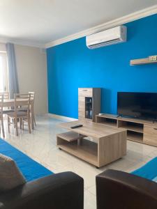 - un salon avec un canapé, une télévision et une table dans l'établissement Modern SeaFront 3bedrooms Apartment, à San Pawl il-Baħar