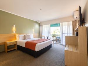 um quarto de hotel com uma cama e uma varanda em Auckland Rose Park Hotel em Auckland