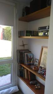 un estante de libros con libros y una cruz en una ventana en La casita anaranjá, en Villa Allende 14 fotos más