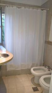 uma casa de banho branca com um WC e um lavatório em La casita anaranjá em Villa Allende