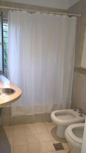 Un baño blanco con inodoro y lavabo. en La casita anaranjá, en Villa Allende