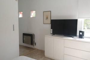 uma sala de estar com televisão numa parede branca em La casita anaranjá em Villa Allende