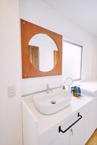 un bagno bianco con lavandino e specchio di 「まちのオアシス」STAY UWU 005 空を眺める半露天風呂 a Kochi