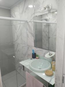 a white bathroom with a sink and a shower at LINDA CASA DE PRAIA EM PIRATININGA in Niterói