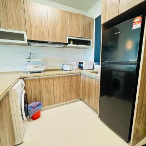 uma cozinha com um frigorífico preto e armários de madeira em Forest city Sea view homestay em Gelang Patah