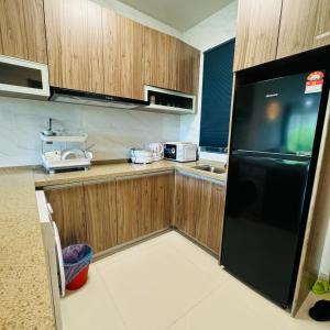 uma cozinha com armários de madeira e um frigorífico preto em Forest city Sea view homestay em Gelang Patah