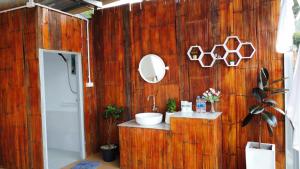 uma casa de banho com uma parede de madeira, um lavatório e um espelho. em หลงฮักเขาแคมป์ปิ้งภูชี้ฟ้า em Ban Huai Khu