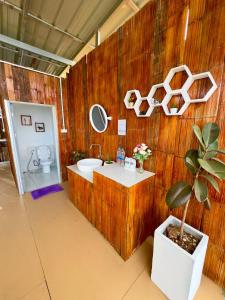 a bathroom with a wooden wall with a sink and a plant at หลงฮักเขาแคมป์ปิ้งภูชี้ฟ้า in Ban Huai Khu