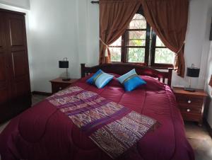 1 dormitorio con cama roja y almohadas azules en Le Paradis sur Kos Samui,bang po plage, en Ban Bang Po