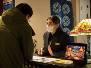 a woman in a face mask sitting at a table with a woman with a laptop at Yufuin Lamp no Yado in Yufuin