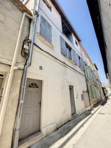 a white building with doors and windows on a street at L'appart d'Avignon in Avignon +2 photos