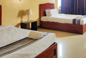 a bedroom with two beds and a table with a lamp at RedDoorz @ ARRS HOTEL & RESORT in Tagum