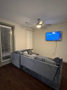 a living room with a couch and a tv on the wall at Vacation Rental Home with Pool/Skyline View Near Galleria Mall in Houston
