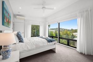 a white bedroom with a bed and a large window at 153 Centenary Heights Rd in Yaroomba +6 photos