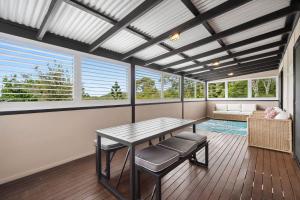 a dining room with a table and chairs and windows at 153 Centenary Heights Rd in Yaroomba