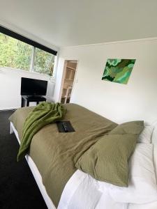 um quarto com uma cama com um cobertor e uma secretária em Double Bedroom with Private Bathroom em Porirua